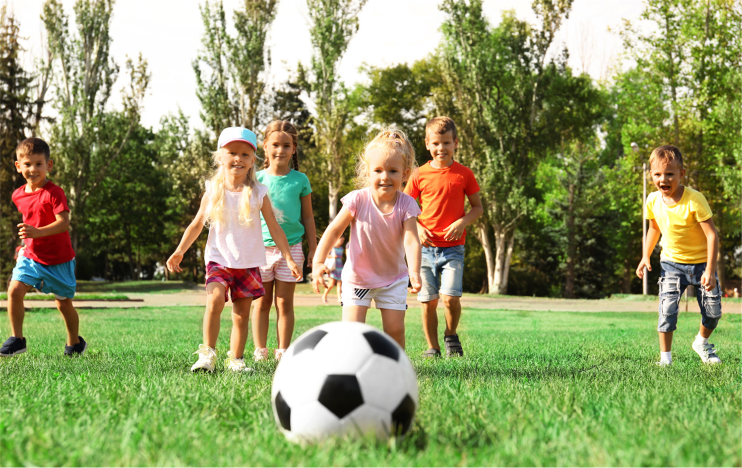 Обучение игре в мяч. Дети на газоне. Играющие дети. Дети улицы. Мяч для детей.